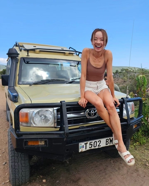 Tourist sitting on the front of a Toyota safari vehicle.