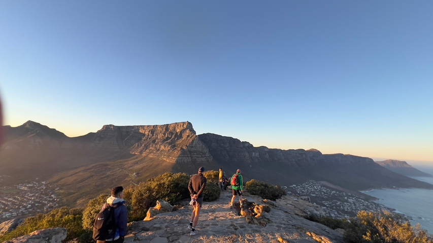       Tourists standing on a peak with a view of mountain range.
  