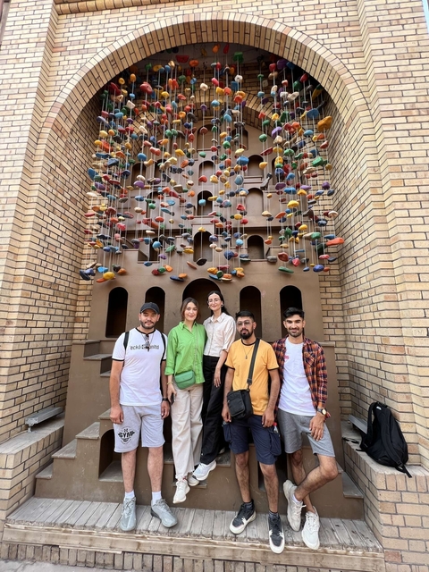 Group of people posing in front of a colorful wall.