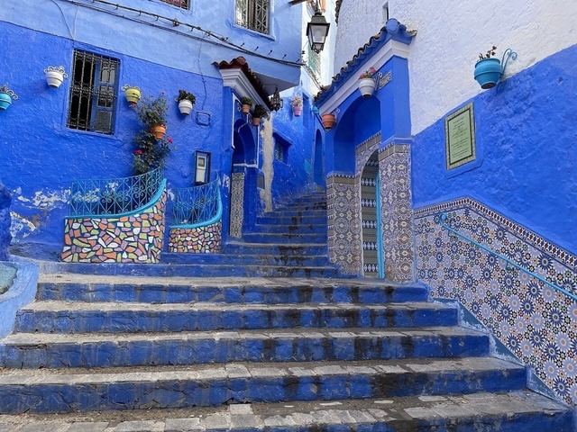       Vibrant blue staircase with artistic tiles in a medina.
  