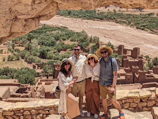       Group of tourists in Ait Benhaddou with traditional buildings.
  