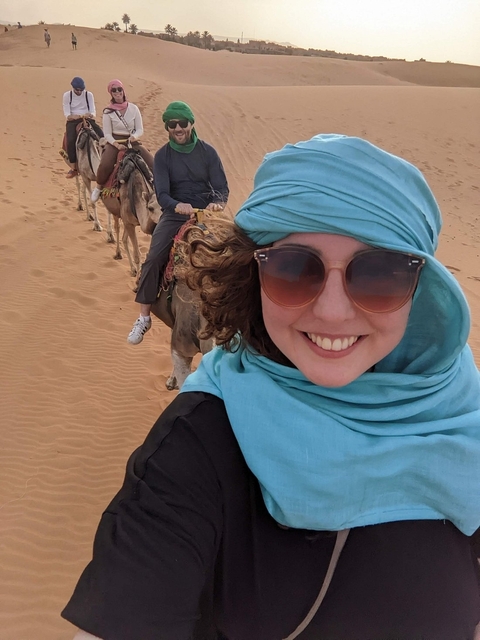       Tourist taking a camel ride in the desert.
  