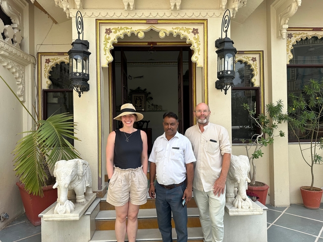       Tourists posing at an entrance with traditional architecture.
  