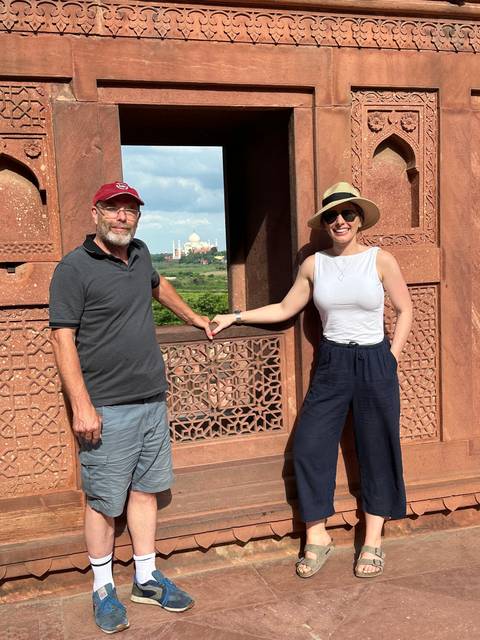       Tourists holding hands with Taj Mahal in background.
  