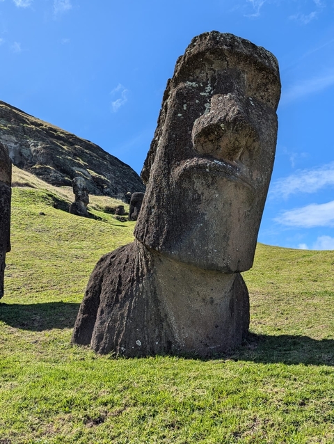 Close-up of a Moai statue in a wide open field.