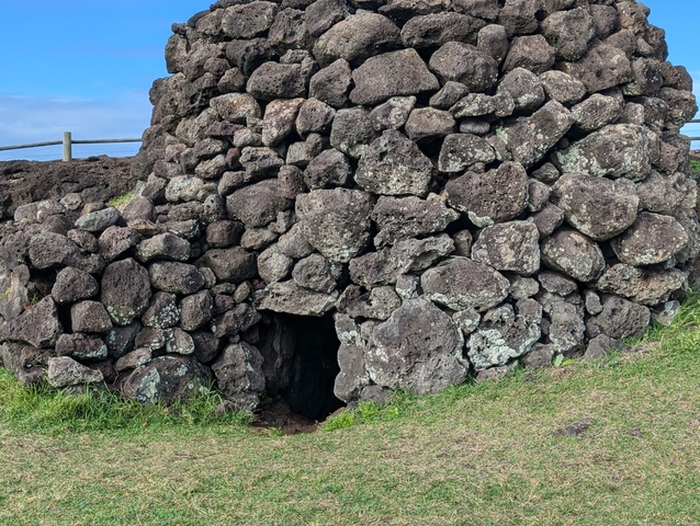       Rocky structure with a small entrance near grassy terrain.
  
