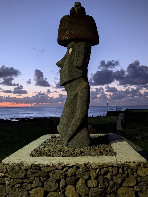       Moai statue against a sunset sky at the ocean.
  