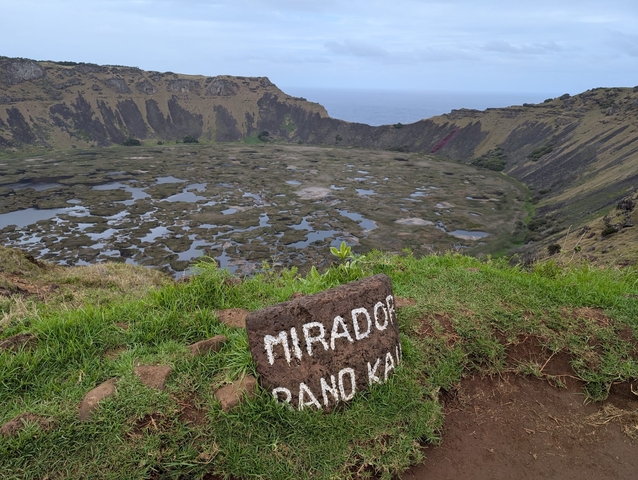 View of a volcanic crater with a sign at the forefront.