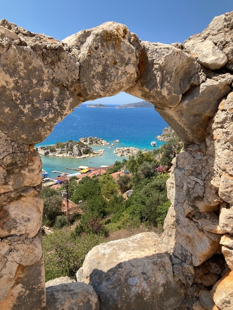 Scenic view of the coast through a stone arch with blue water and islands.
