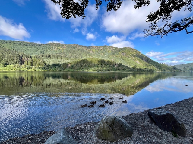 Calm lake with reflective water surrounded by mountains.