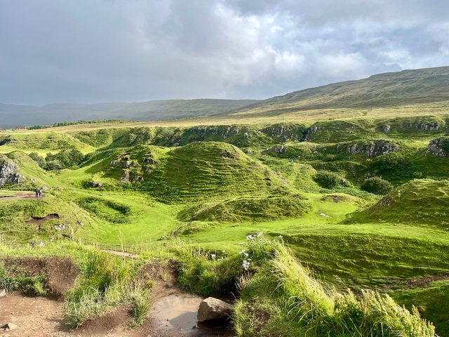 Scenic green hills under a cloudy sky.