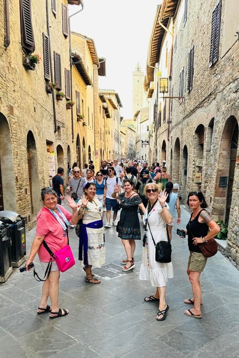       A busy street scene with a group of women waving.
  