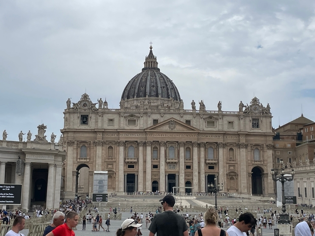       St. Peter's Basilica in Rome with tourists in front.
  