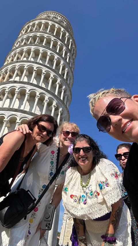       Group of people posing in front of the Leaning Tower of Pisa.
  