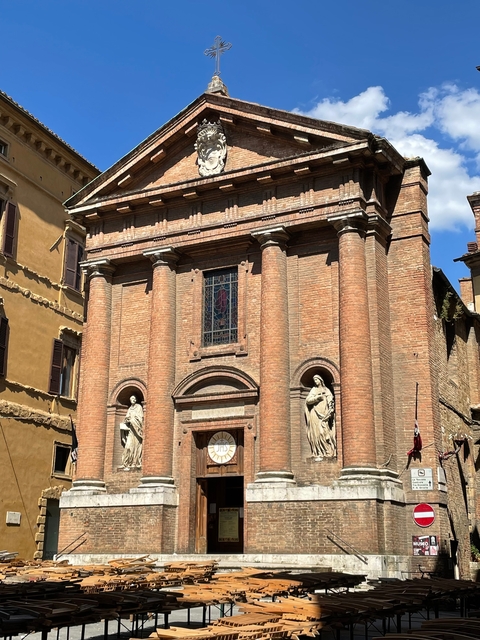       A brick church with statues and decorative windows.
  