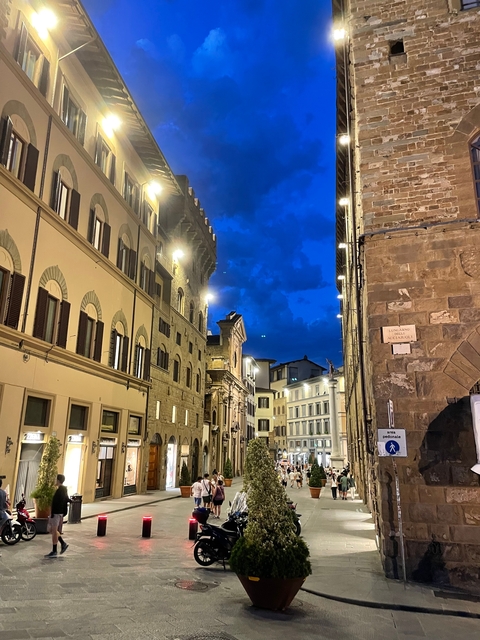       Night scene of a street with lights illuminating buildings.
  
