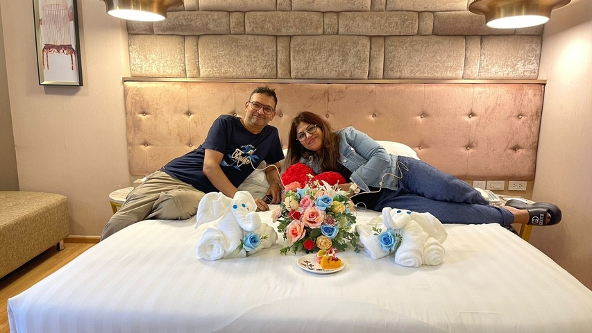 Couple reclining on a bed with towel animals and flowers.