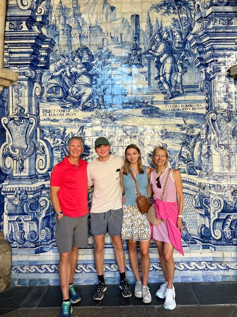       A family posing in front of a tile mural.
  