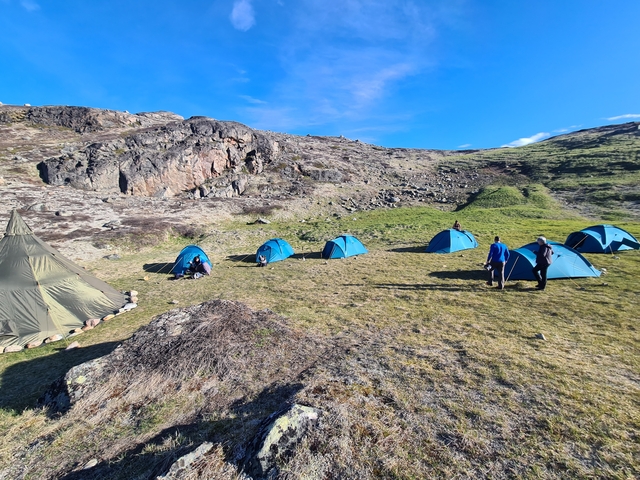      Camping tents set up in a rocky landscape under a clear sky.
  