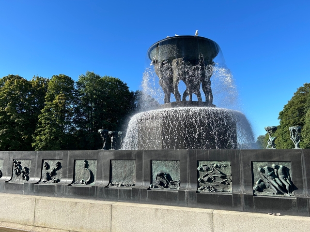       Cascading water feature with intricate sculptures in a park.
  