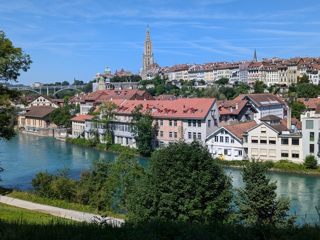 Cityscape showing buildings and a river with a prominent gothic-style tower.