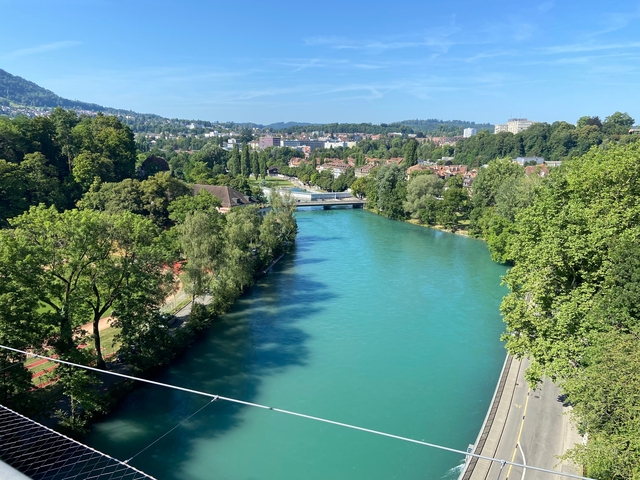 Turquoise river flowing through a city with bridges crossing it.