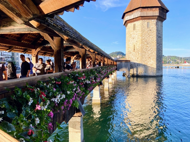 A famous covered wooden bridge over water with people walking.
