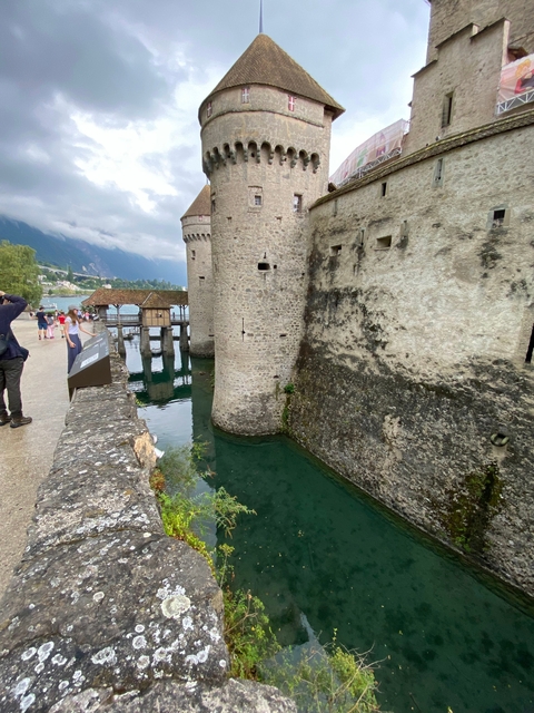 Stone castle walls next to a calm body of water.
