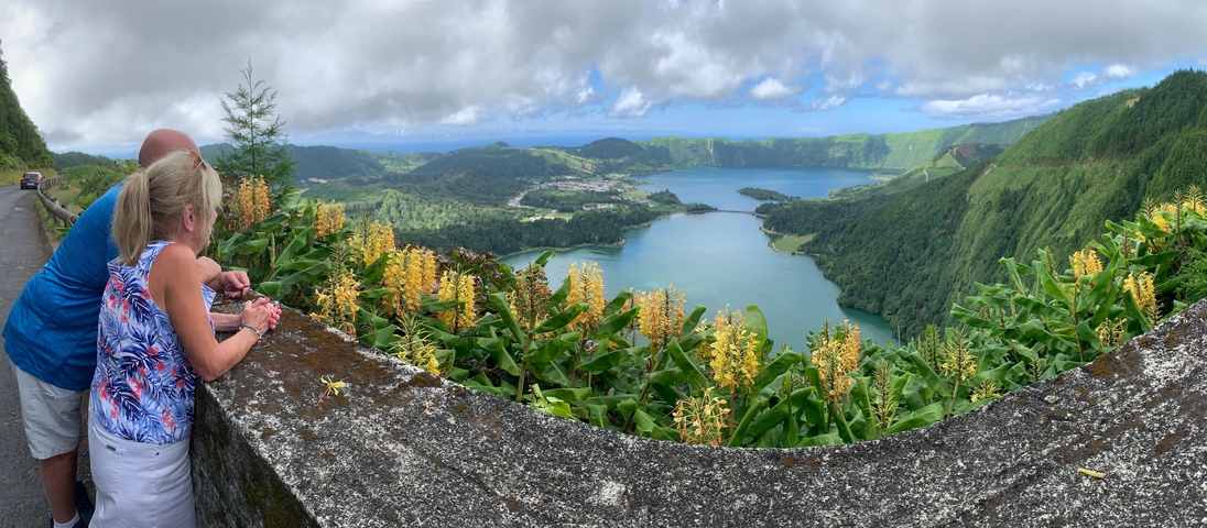 Couple enjoying a scenic view of a lake surrounded by hills.