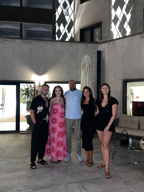 Group of people posing indoors by a wall.