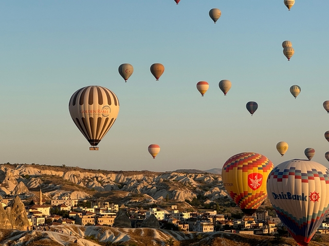 Hot air balloons floating over a rocky landscape during the day.