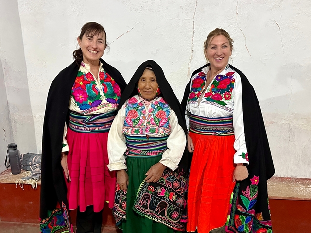      Three women in vibrant traditional attire posing.
  