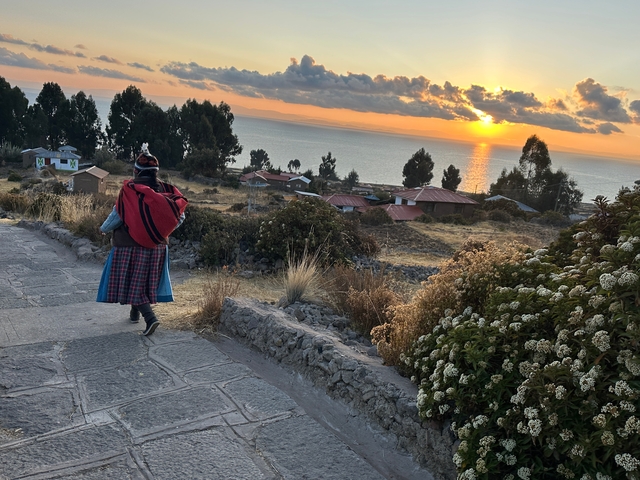       Person walking on a path with sunset over the sea.
  