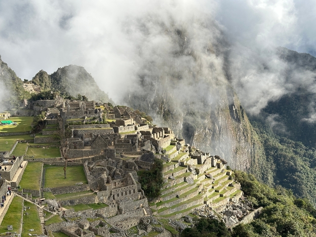      Machu Picchu ruins with mist and mountain backdrop.
  