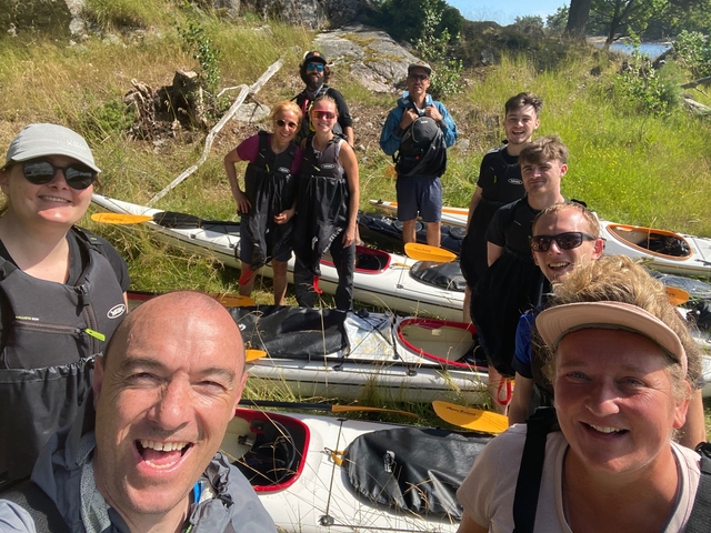 Group of people in kayaking gear posing with kayaks.
