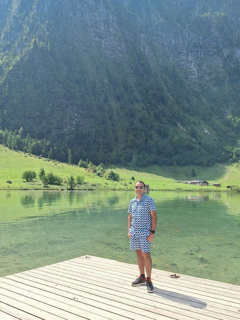       Man in front of a tranquil lake with mountain background.
  
