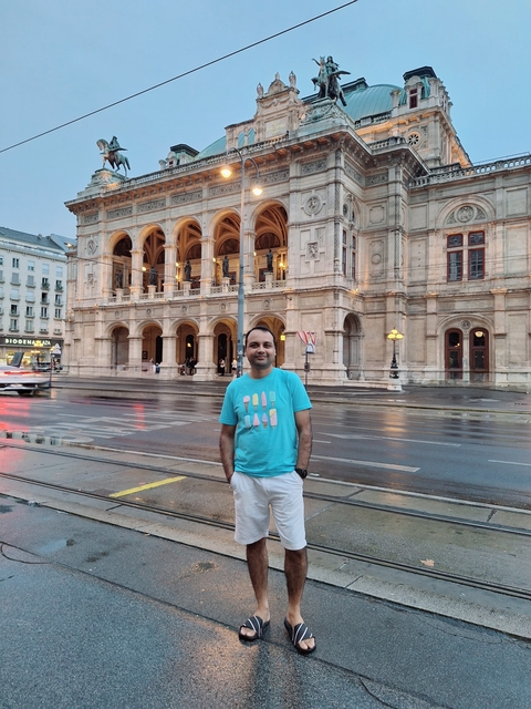      Man posing in front of a historic building in a city.
  