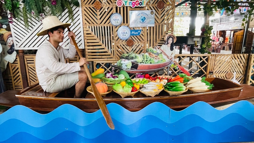 Person sitting in a boat with fruit display in a marketplace.