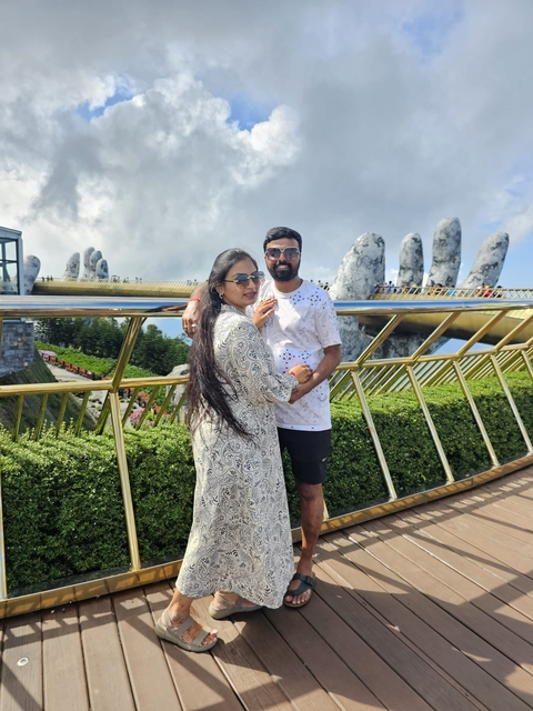       Couple posing on a bridge with mountainous background.
  