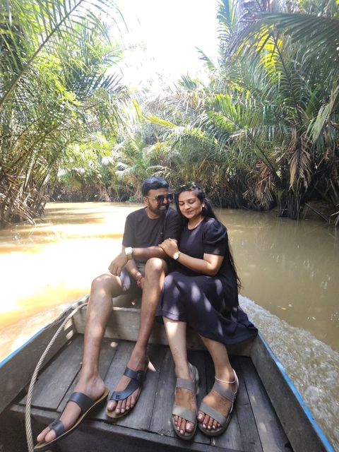       Couple sitting in a boat on a river surrounded by greenery.
  