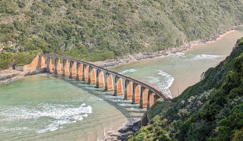       A bridge crossing over a river with surrounding lush greenery.
  