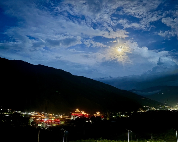       Moonlit landscape with illuminated temples and clouded sky.
  
