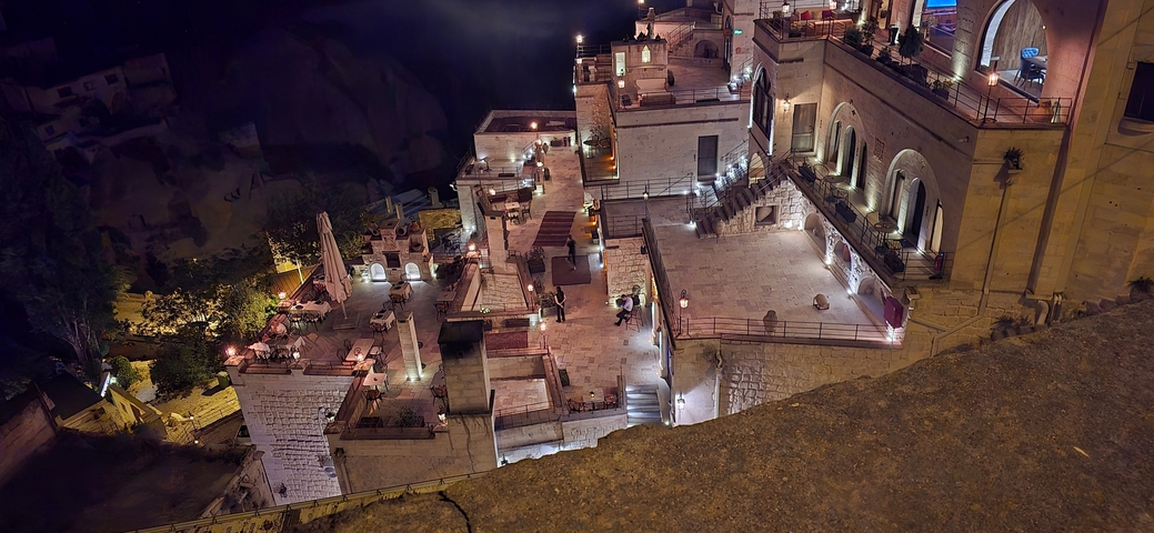 Nighttime view of a stone terrace with lighting and ornamentation.