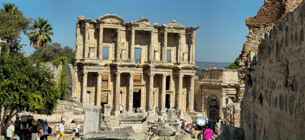 Ancient library ruins with tourists around in an archaeological site.
