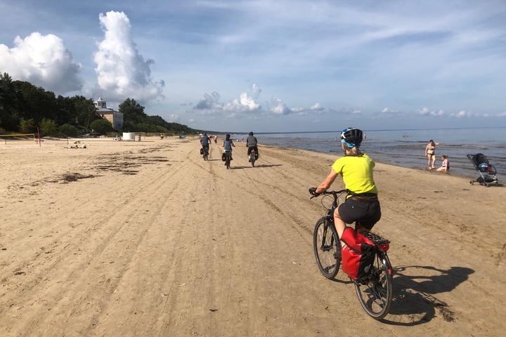 Cyclists riding along a sandy beach.