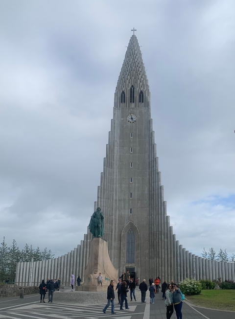 Church with a prominent tower and a statue in front.