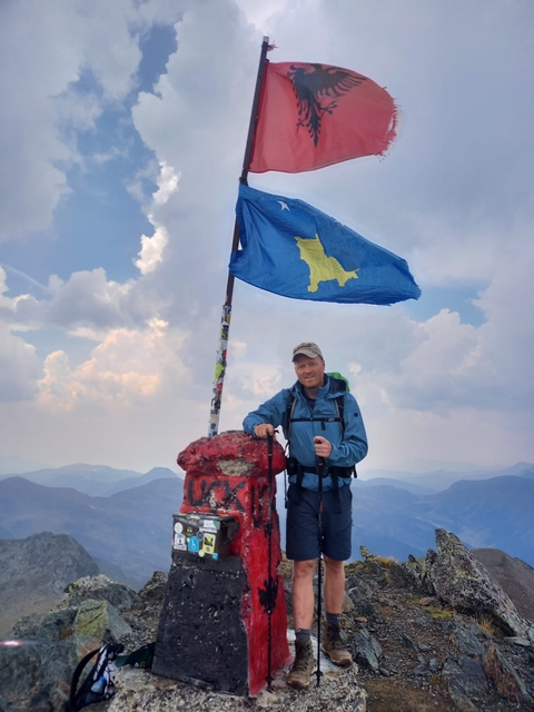 Person standing on a mountain with a flag.