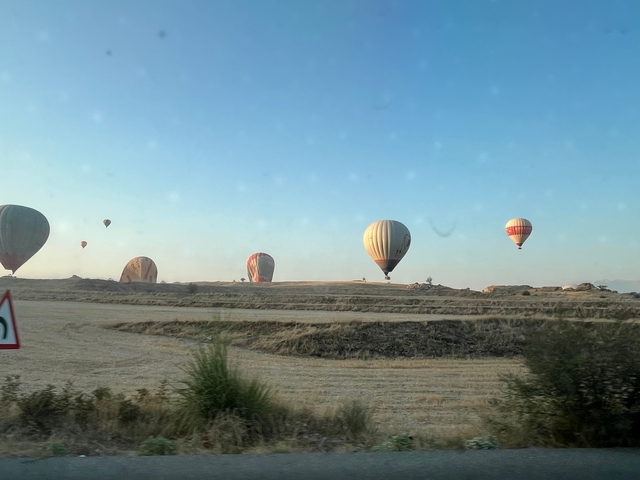 Hot air balloons in a clear sky over dry landscape.