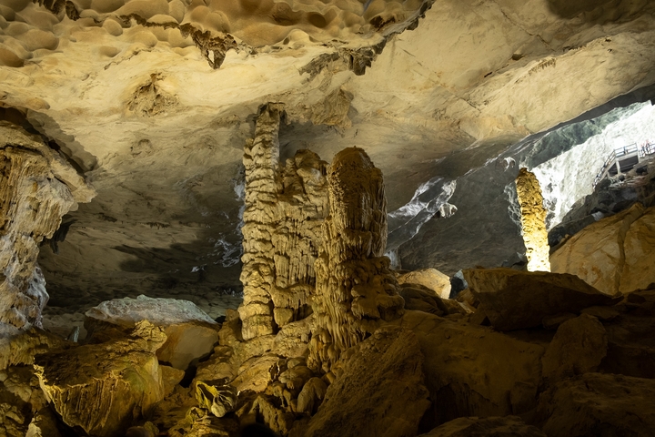 Inside a cave with illuminated stalactites and stalagmites.