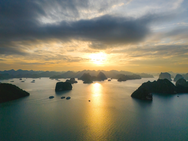 Sunset over Halong Bay with silhouetted karst islands.
